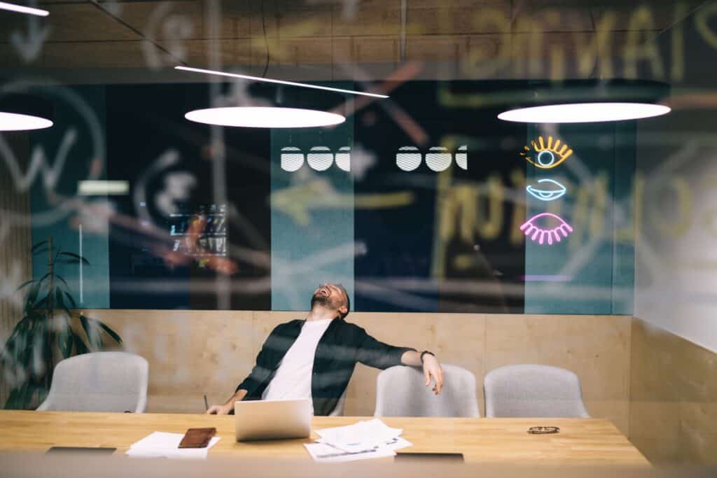 Tired businessman leaning back in chair at workplace in office
